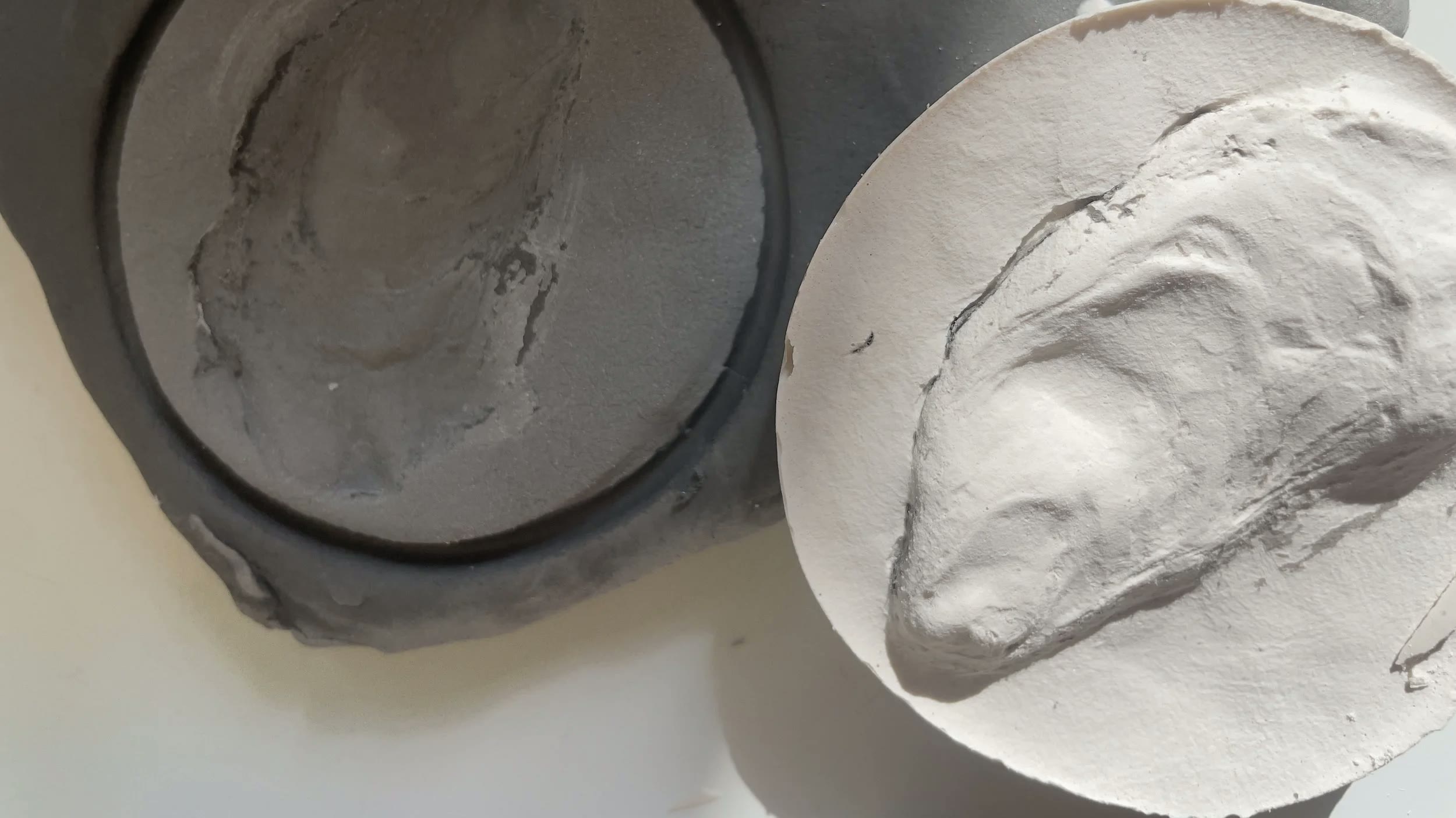 Close-up of a hand-worked plaster sculpture surface in raking studio light